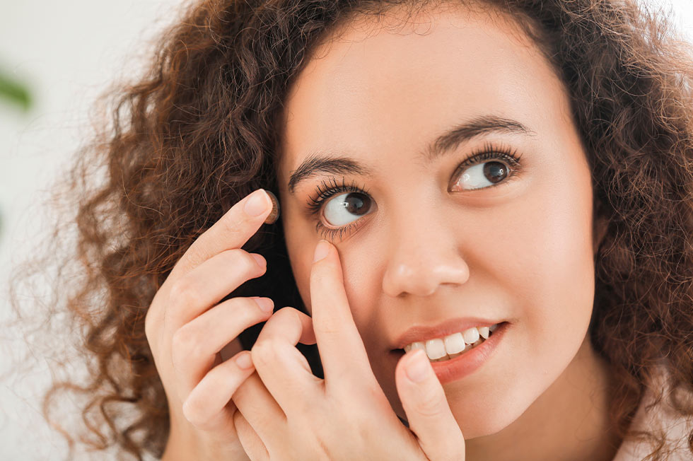 Woman putting on her contact lens at Bristol Family Eyecare